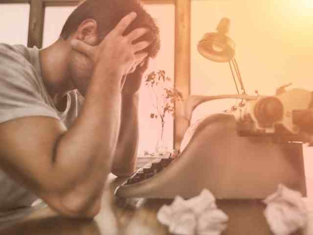 Man suffering from writer's block with holding his head