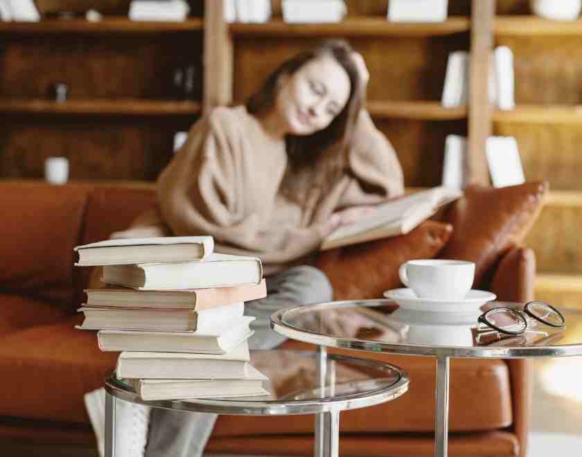 women sitting in cafe with a stack of writing craft books on the table in front of her