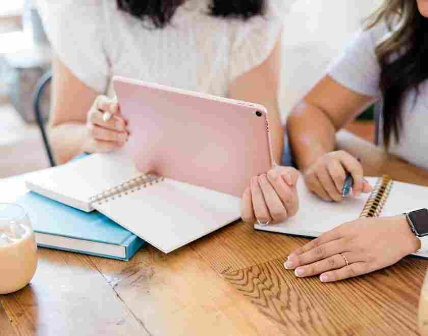 WOman with pink ipad working with a book coach
