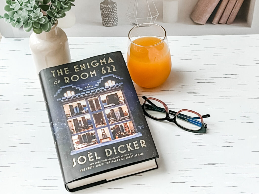 The Enigma of Room 622 book with glasses, vase and drink